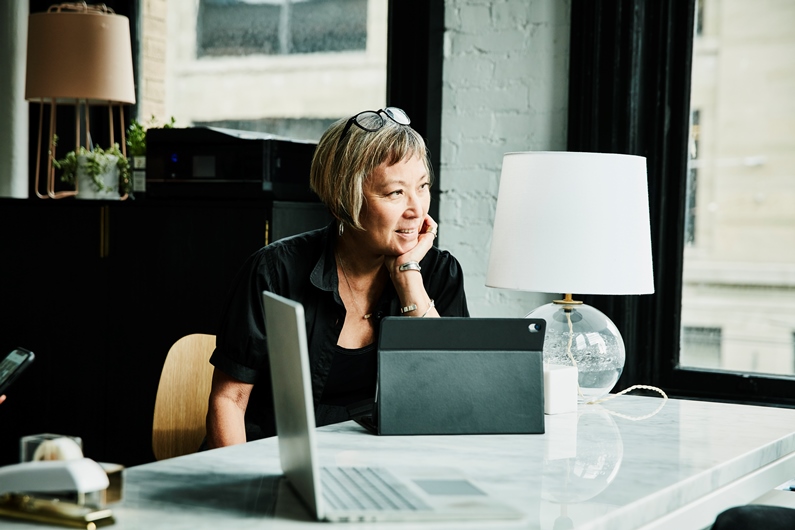 a woman at a desk with a tablet and computer