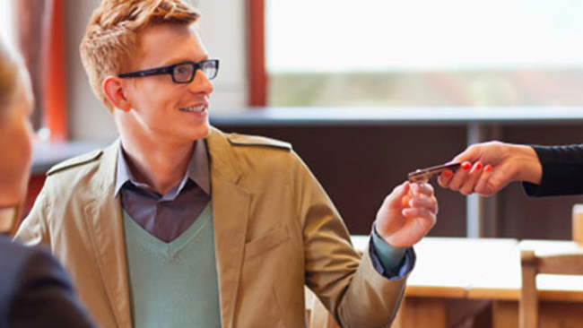 man smiling and passing a debit card to another person
